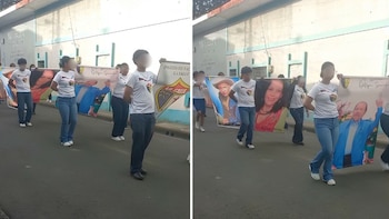 Jóvenes con uniformes escolares alineados en la calle sostienen banderas pequeñas de Nicaragua y del FSLN