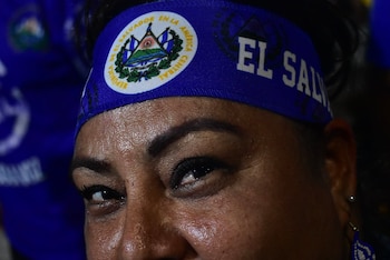 Primer plano del rostro de una mujer que lleva una cinta azul en la frente con el escudo de El Salvador