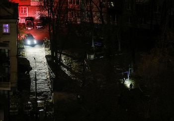 Un coche pasa junto a un vecino que camina con una linterna junto a unos edificios residenciales durante un corte de electricidad, en medio del ataque de Rusia a Ucrania, en Kiev (Ucrania) (REUTERS)