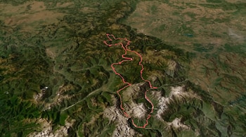 Vista aérea de un paisaje montañoso con picos y valles. Una línea roja serpenteante traza un recorrido sobre el terreno irregular.