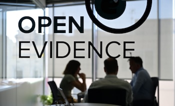Letrero 'OPEN EVIDENCE' y logo de ojo en cristal. Detrás, tres figuras borrosas de personas en una reunión