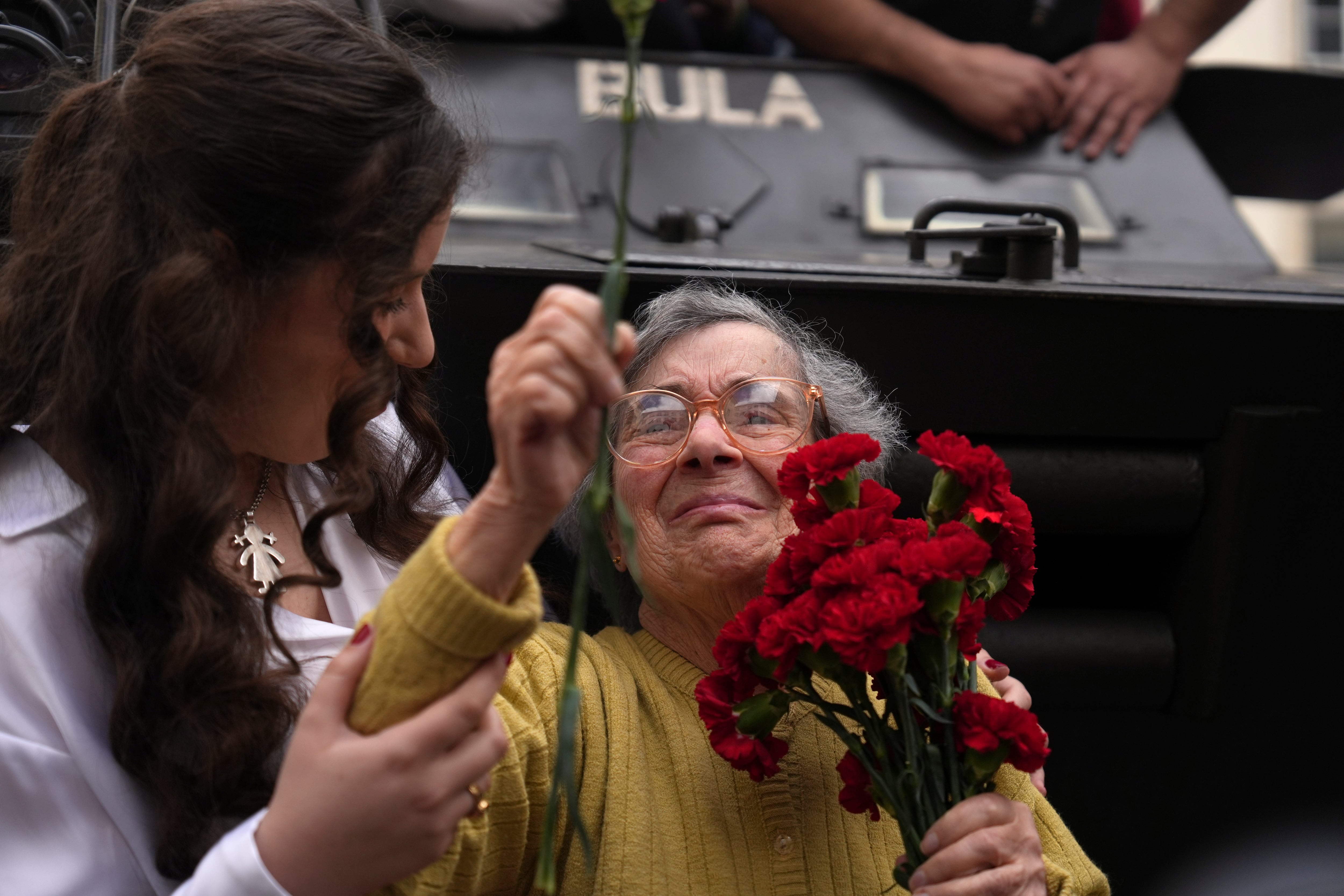 Celeste Caeiro, de 90 años, sostiene un ramo de claveles en Lisboa, Portugal, el jueves 25 de abril de 2024, en la recreación del movimiento de tropas en el 50º aniversario de la revolución lusa. (AP Foto/Ana Brigida)
