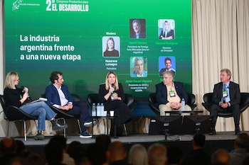 Panel de cinco oradores sentados en un escenario frente a una pantalla verde con el título "2º Congreso Productivo", y una audiencia borrosa en frente