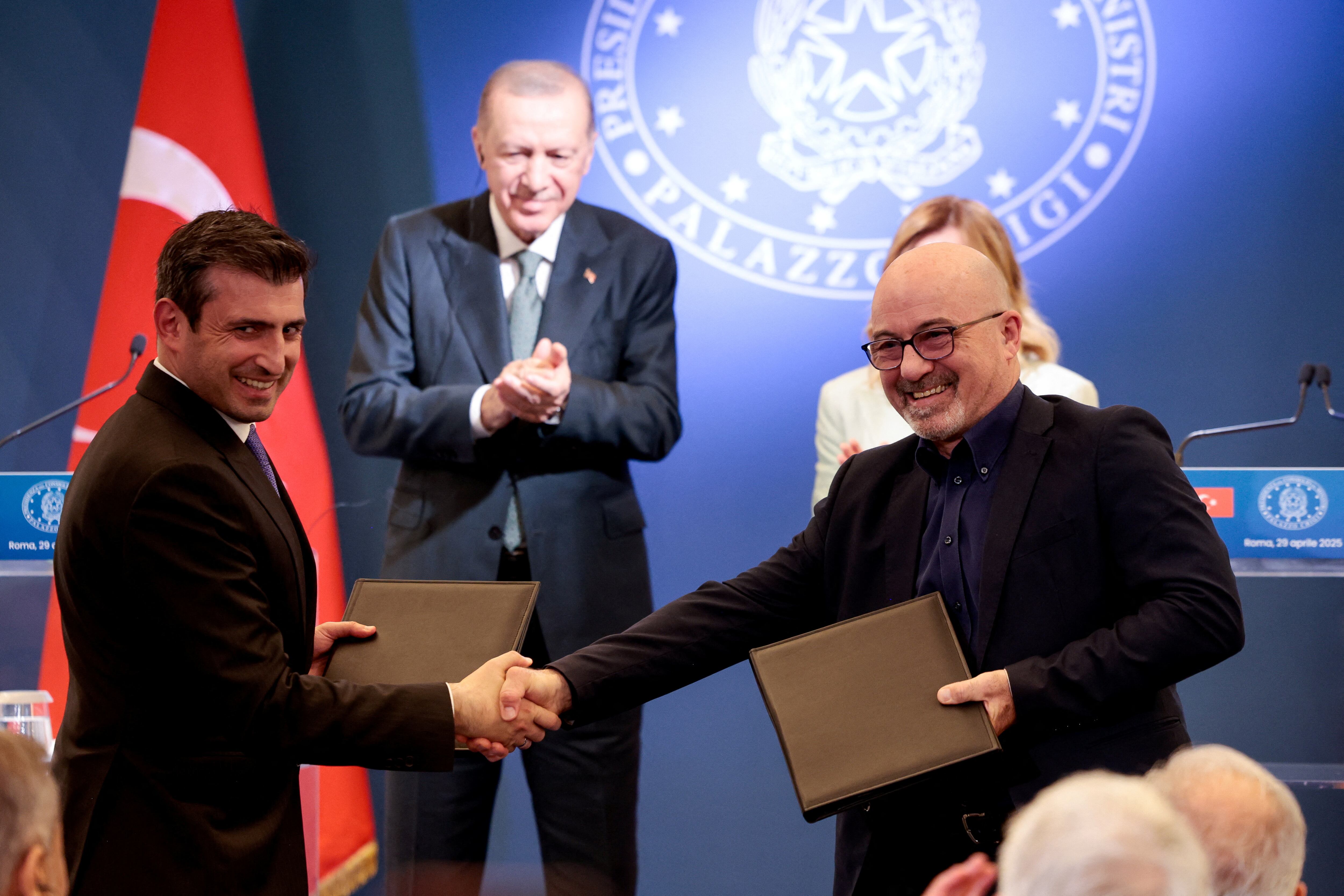 El director ejecutivo de Leonardo, Roberto Cingolani, estrecha la mano del director de tecnología de Baykar, Selcuk Bayraktar, durante un acuerdo, mientras la primera ministra italiana, Giorgia Meloni, y el presidente turco, Tayyip Erdogan, ofrecen una conferencia de prensa en Villa Doria Pamphili en Roma, Italia, el 29 de abril de 2025. REUTERS/Remo Casilli