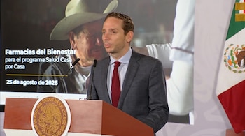 Hombre con traje en un podio de México ante una pantalla con el texto Farmacias del Bienestar y una bandera mexicana a su derecha.