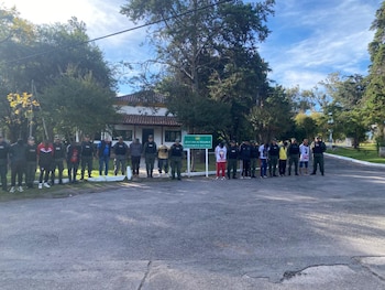 Agentes de Gendarmería Nacional y civiles parados en una calle de asfalto. Al fondo, un edificio y un cartel que indica 'Jefatura de Región IX Gendarmería Nacional'