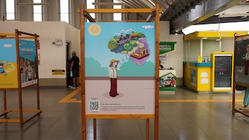 Panel de exposición en el Metro de Lima con una ilustración de Antonio Raimondi y globos de pensamiento que muestran un tren y equipos científicos