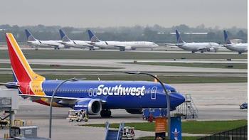 Avión azul y rojo de Southwest Airlines en primer plano en una pista de aeropuerto, con varios aviones blancos de United Airlines en el fondo