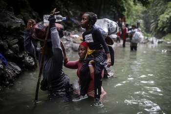 Migrantes haitianos vadean un río