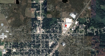 Imagen satelital aérea de una zona urbana y rural con edificios, calles, árboles y cuerpos de agua. Un marcador rojo indica 415 E Prairie Ronde Street
