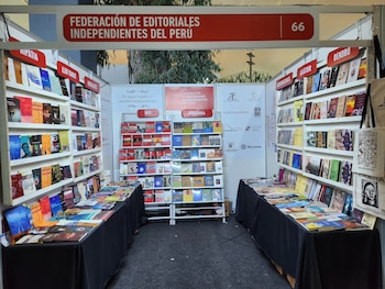 Un puesto de feria con estantes y mesas con libros impresos bajo un letrero de la Federación de Editoriales Independientes del Perú