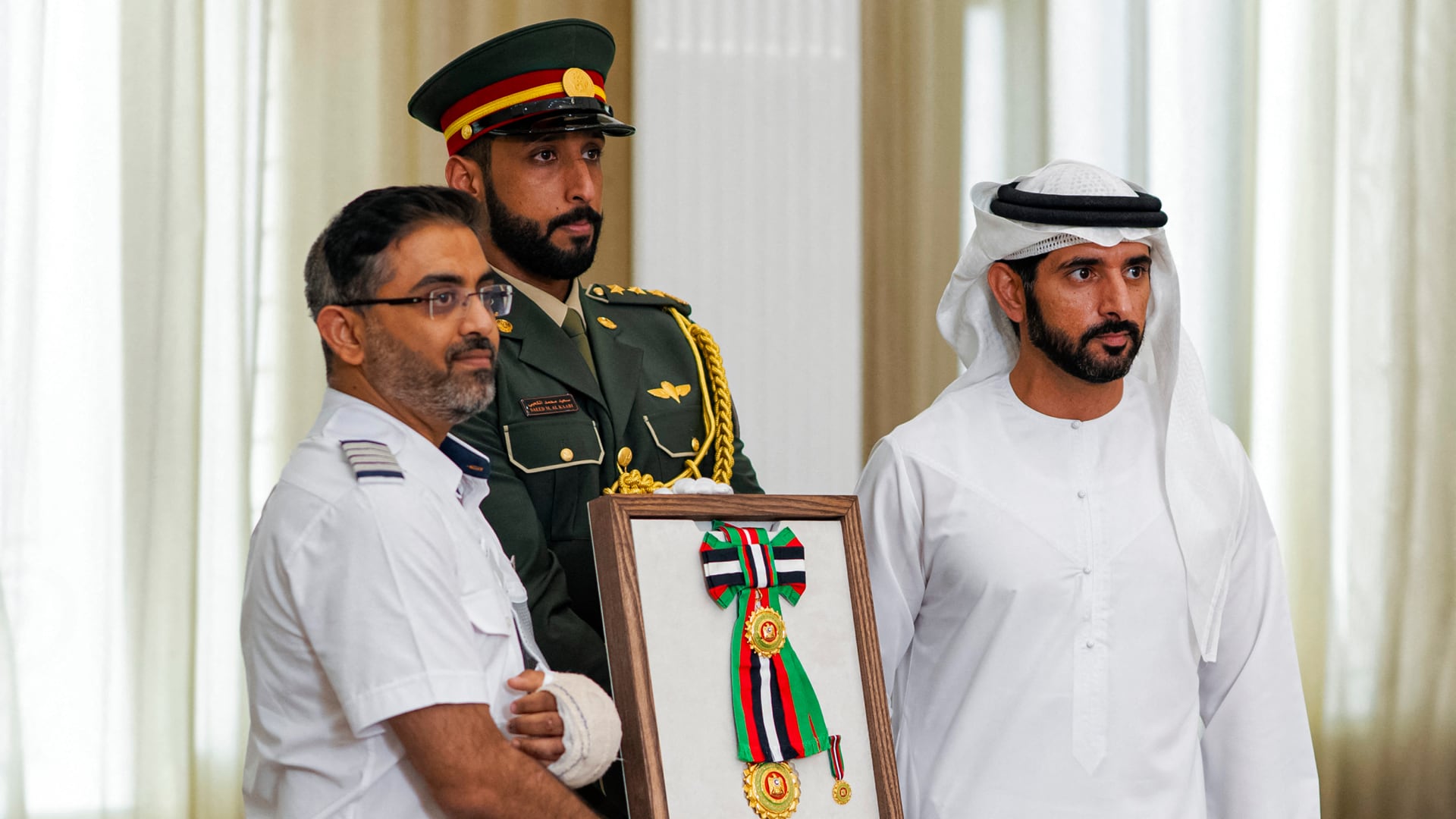 El Viceprimer Ministro y Ministro de Defensa de los EAU, el Jeque Hamdan bin Mohamed Al-Maktoum, entregando la Orden de Zayed II, de Primera Clase, al piloto de Flydubai, Smit Machchhar, durante el homenaje que él y otros miembros de la tripulación del vuelo 1073 recibieron en Abu Dabi el 27 de octubre de 2026 (AFP)