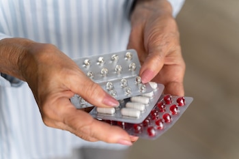 Una mujer sostiene varios blísters con antibióticos (Freepik)