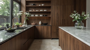 Vista de una cocina moderna con gabinetes de madera oscura, encimeras de mármol negro y una isla de mármol blanco. Hay un piso de baldosas claras y una ventana grande.