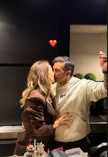 Primer plano de Fabián Cubero y Mica Viciconte besándose. Ella lleva un blazer marrón, él una sudadera clara. Hay un pastel y un corazón rojo en la imagen