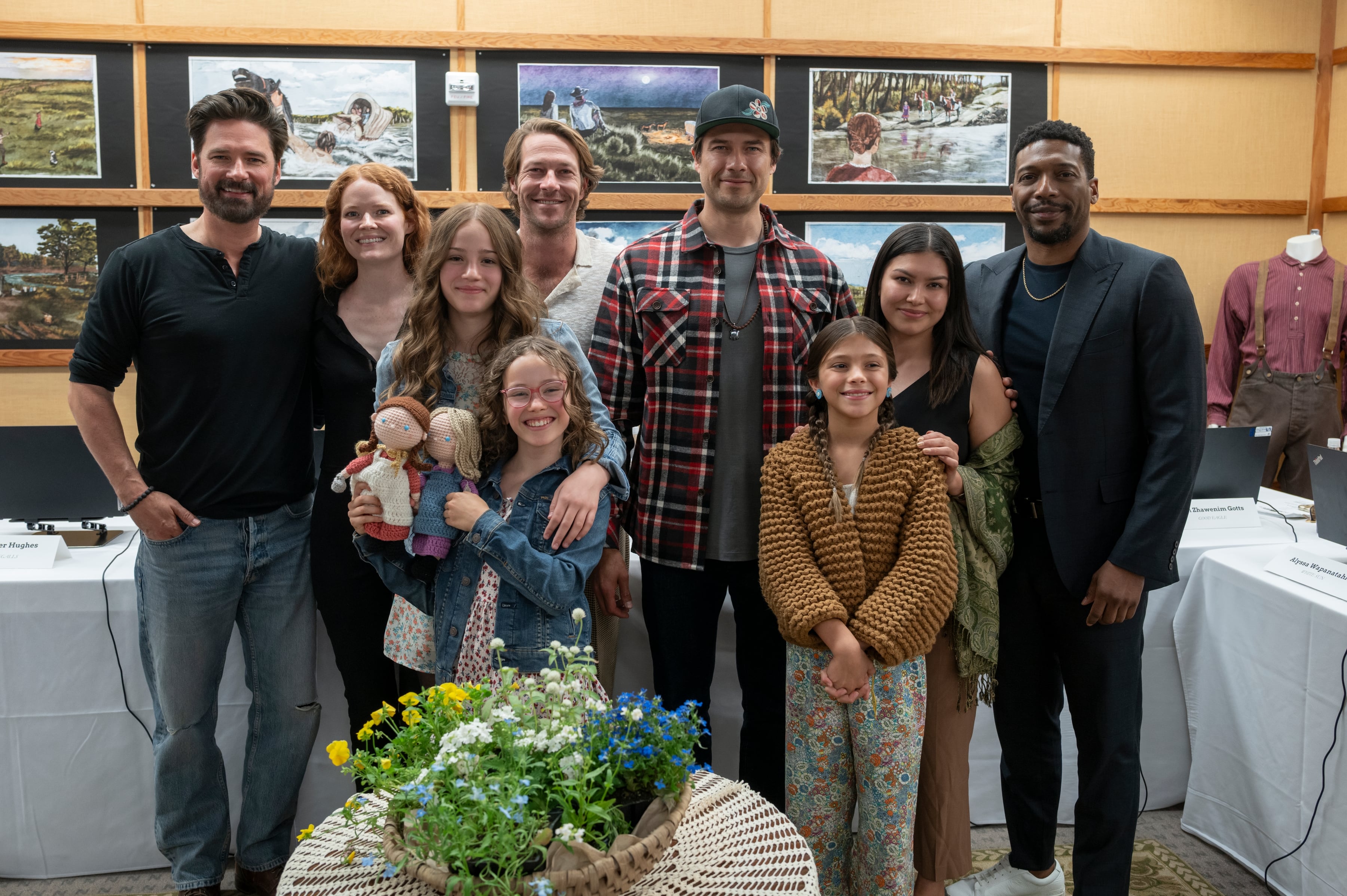 Luke Bracey, Crosby Fitzgerald y el equipo de un proyecto inspirado en el legado de Michael Landon posan para una foto grupal rodeados de arte temático y conmemorativo de 'La Casa de la Pradera'. (Netflix)