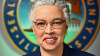 Retrato en primer plano de Toni Preckwinkle con gafas y cabello corto canoso frente al sello circular del Condado de Cook