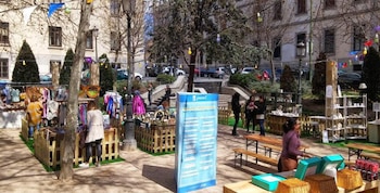 Una parte del mercadillo en una plaza, con ropa, productos artesanales y botes de frutas.