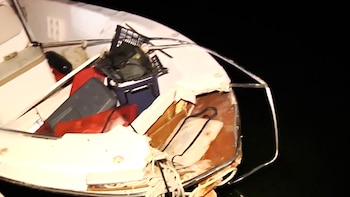 Proa de una embarcación Sea Ray blanca con daños, incluye maderas rotas, cuerdas, una cesta negra y varios objetos rojos en el interior. Fondo oscuro