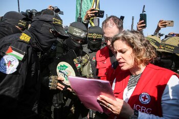 Militantes palestinos observan mientras miembros del Comité Internacional de la Cruz Roja (CICR) esperan para recibir rehenes.