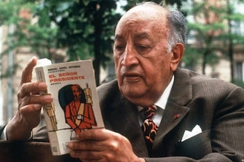 Fotografía en blanco y negro de Miguel Ángel Asturias de traje mientras sostiene un ejemplar del libro Mulata de tal