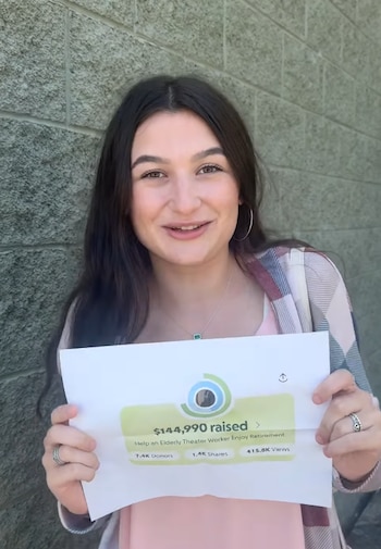 Una mujer joven con cabello oscuro sonríe, sosteniendo un papel que muestra el monto de USD 144,990 recaudados en una campaña de fondos