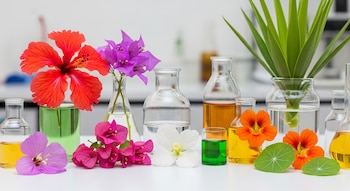 Flores comestibles y frascos de laboratorio con líquidos de colores sobre una mesa blanca
