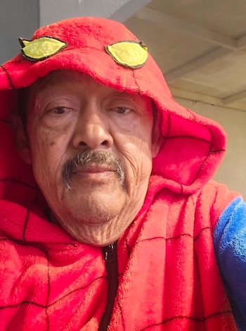 Primer plano de un hombre mayor con bigote que viste una sudadera roja con capucha de peluche y detalles de ojos amarillos