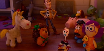Unicornio de peluche, erizo de peluche, Woody, Forky, Señor Cara de Papa, Dolly, Rex, Hamm y Slinky Dog en un piso de madera