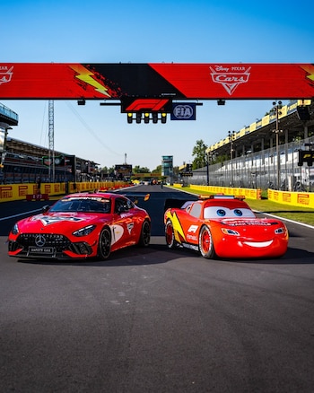 Un automóvil de carreras rojo y un vehículo con la forma del personaje Rayo McQueen están sobre la pista frente a un portal publicitario