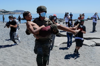Soldado español con un niño que cruzó a Ceuta en 2021 (REUTERS/Jon Nazca9