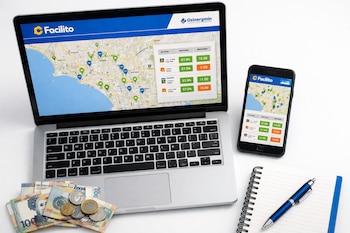 Laptop y smartphone mostrando la web Facilito con mapa de Lima y precios de combustible. Billetes y monedas peruanas, libreta y bolígrafo en escritorio blanco.