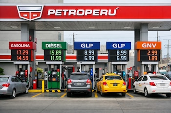 Estación de servicio Petroperú con surtidores de gasolina, diésel, GLP y GNV. Paneles digitales muestran los precios. Cuatro vehículos en fila.