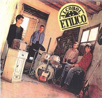 Cuatro hombres posan con instrumentos musicales (batería, guitarras eléctricas) y un mueble antiguo en una habitación rústica; el logo 'Alcohol Etílico' se ve en la parte superior