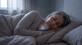 Una mujer duerme de lado en una habitación oscura con un esquema anatómico iluminado en la zona del cuello.