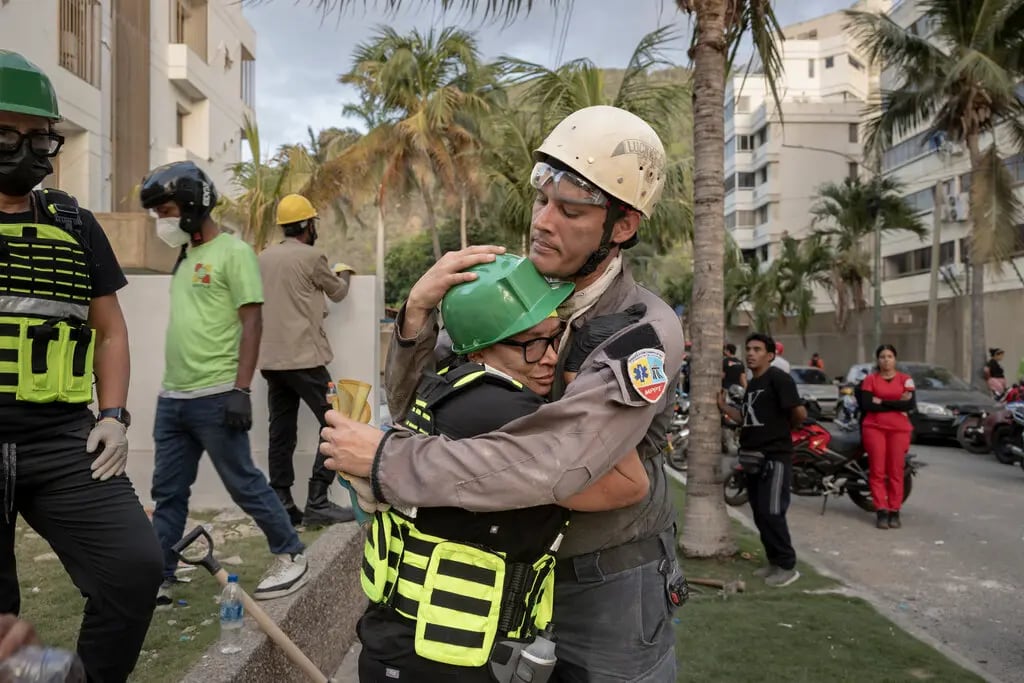 La médica Zaira Medina, a la izquierda, abrazando a un rescatista frente a su bloque de apartamentos derrumbado en La Guaira, Venezuela, el viernes (NYT)