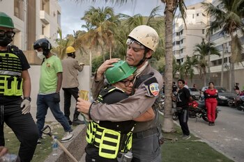 La médica Zaira Medina, a la izquierda, abrazando a un rescatista frente a su bloque de apartamentos derrumbado en La Guaira, Venezuela, el viernes (NYT)