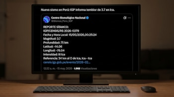 Un monitor de computadora sobre un escritorio de madera exhibe una pantalla oscura con un reporte sísmico del Centro Sismológico Nacional en texto blanco. Un teclado y ratón se ven al frente.
