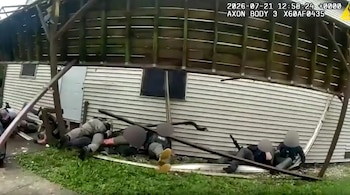 Varios individuos con uniformes policiales yacen en el suelo entre los escombros de una terraza de madera derrumbada junto a un edificio