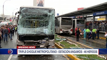 Bus del Metropolitano con parabrisas destrozado tras choque en estación Angamos. Se ven otros buses dañados, personal de emergencia y multitud de personas.
