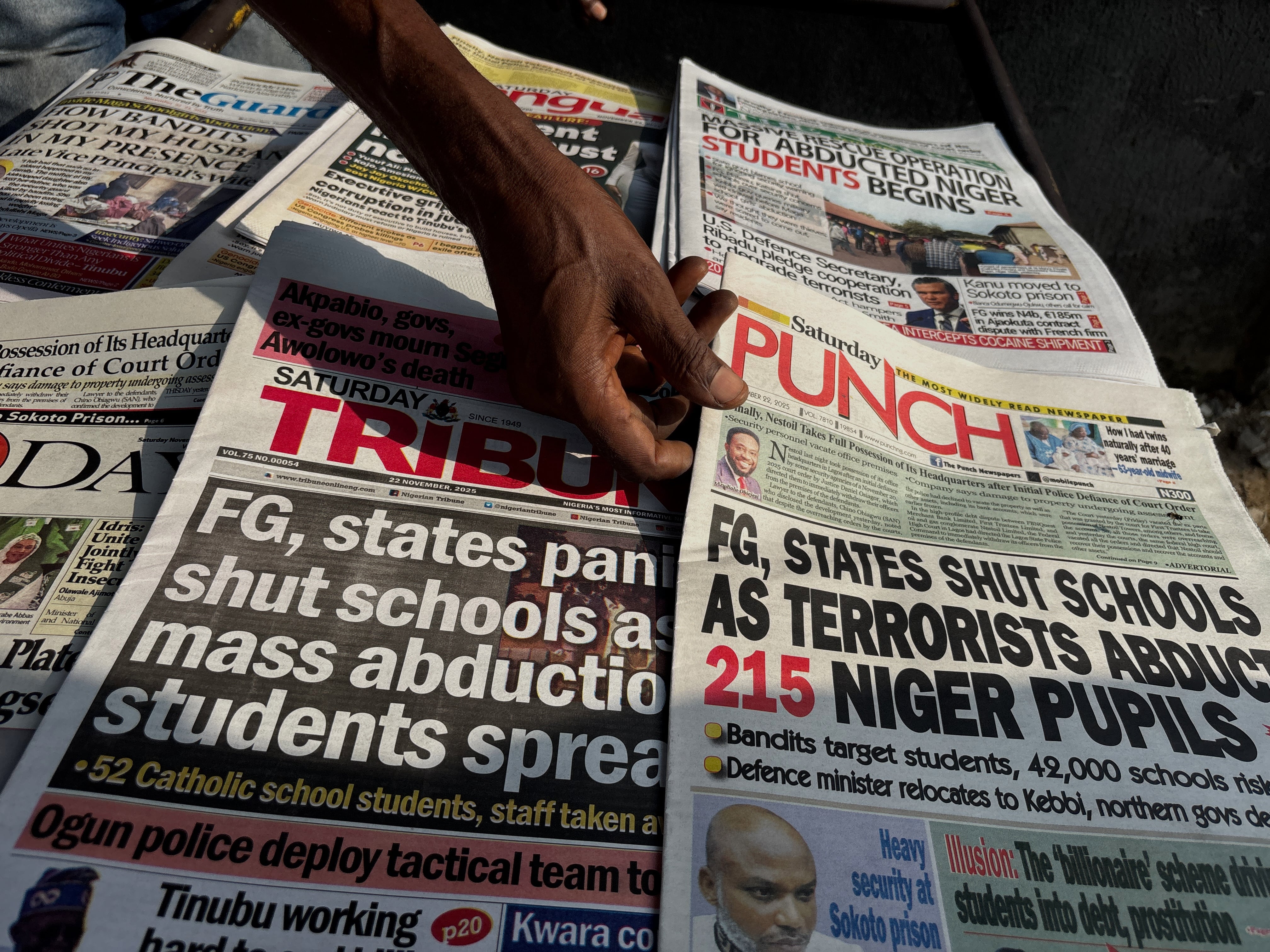 Un vendedor ambulante exhibe portadas de diarios que informan sobre la desaparición de estudiantes de la escuela católica St. Mary, en Lagos, Nigeria (AP)