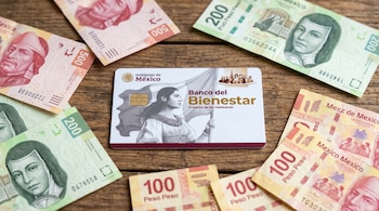 Una tarjeta de débito del Banco del Bienestar en una mesa de madera. La rodean tres billetes de 500 pesos, cuatro de 200 pesos y cinco de 100 pesos.