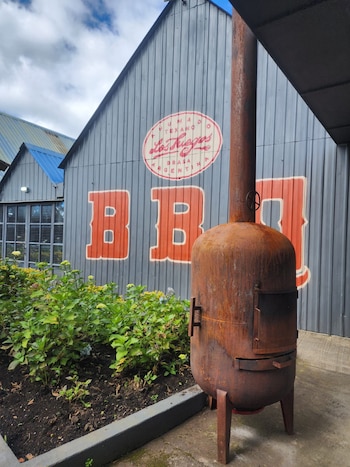 El restaurante está ubicado en un espacio fuera del ruido urbano, en un entorno campestre que acompañe la experiencia de sentarse frente a un corte largo de brisket o una tira de costilla a la parrilla.