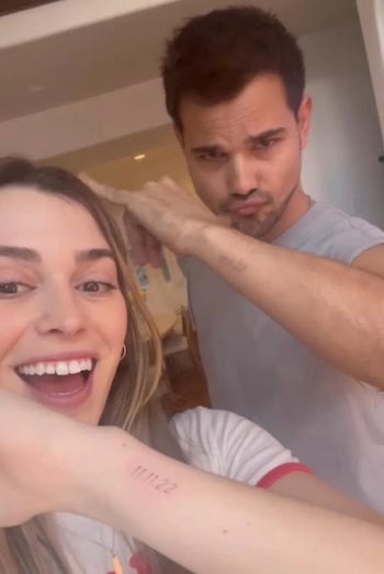 Primer plano de una mujer sonriente y un hombre haciendo una mueca, ambos mostrando sus antebrazos con tatuajes de la fecha "11.11.22"