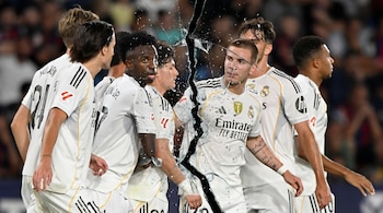 Jugadores de fútbol del Real Madrid con camisetas blancas con franjas negras, con una fractura visual de vidrio roto cruzando el centro de la imagen.