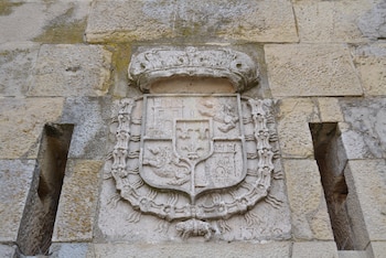 El escudo con los castillos, los leones, la corona encima y más elementos en piedra caliza.
