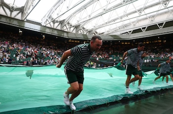 El staff de colaboradores de Wimbledon cubre el césped con una lona al caer la lluvia (Crédito: REUTERS/Toby Melville)