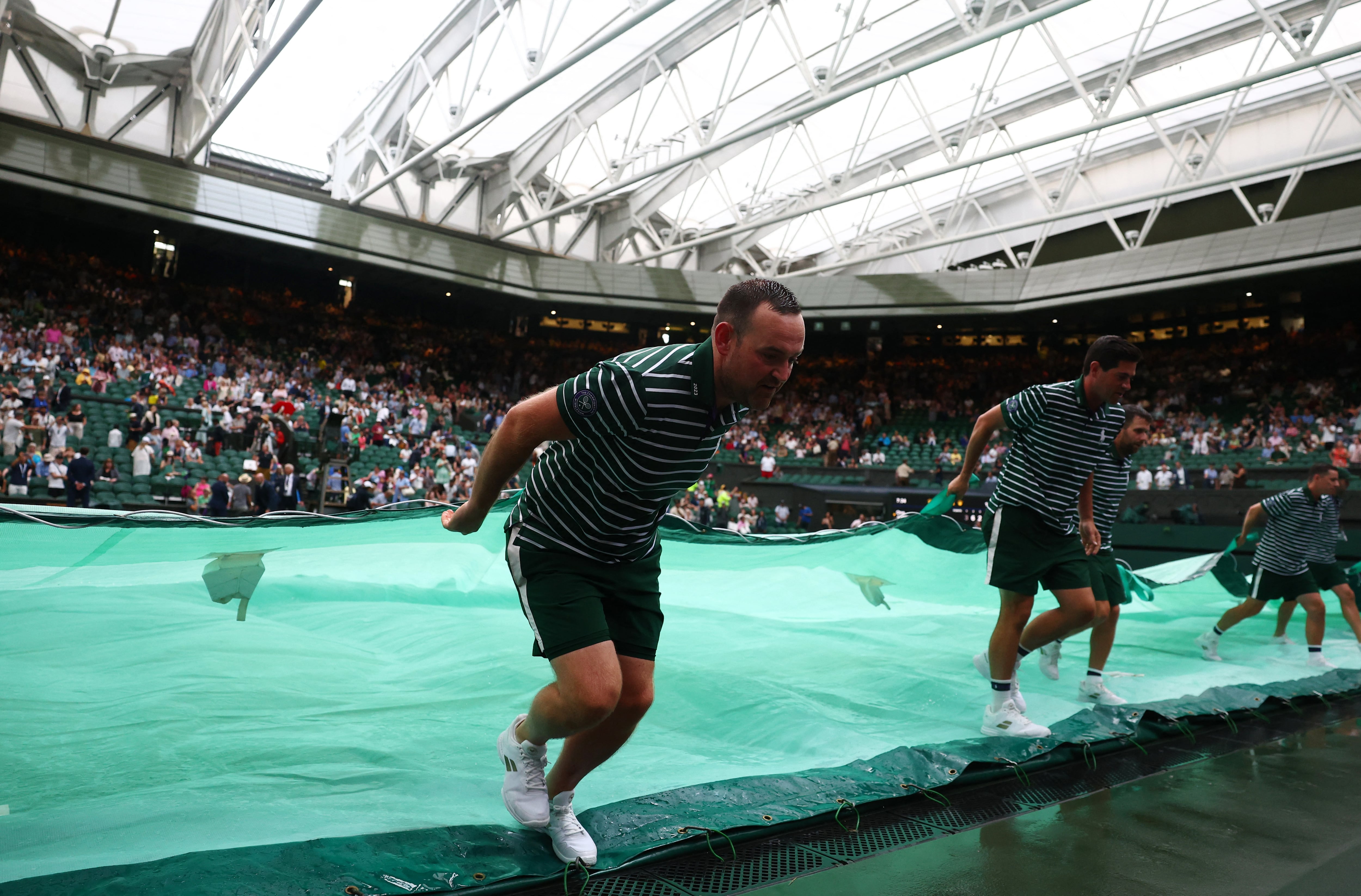 El staff de colaboradores de Wimbledon cubre el césped con una lona al caer la lluvia (Crédito: REUTERS/Toby Melville)