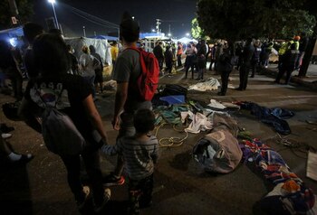 Migrantes se encuentran entre pertenencias personales que fueron esparcidas durante una protesta y luego de que autoridades mexicanas se deshicieran de ellas al instalar una cerca de metal, en un campamento de migrantes cerca del cruce fronterizo de El Chaparral con Estados Unidos, en Tijuana, Mexico. 28 de octubre de 2021. REUTERS/Jorge Duenes