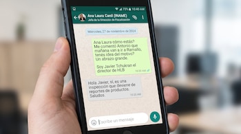Una persona sostiene un teléfono móvil con la aplicación WhatsApp abierta, mostrando un diálogo entre Ana Laura Canil y Javier Tchukran con fecha 27/11/2024.